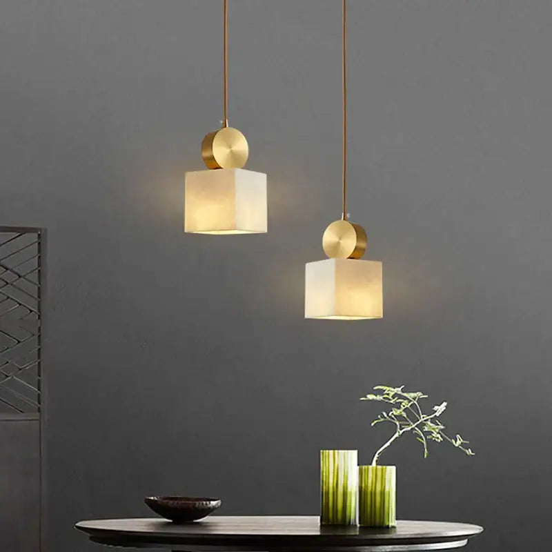 Two minimalist modern golden luxury marble pendant lamps with gold-toned fixtures and frosted glass for dining room decorbites