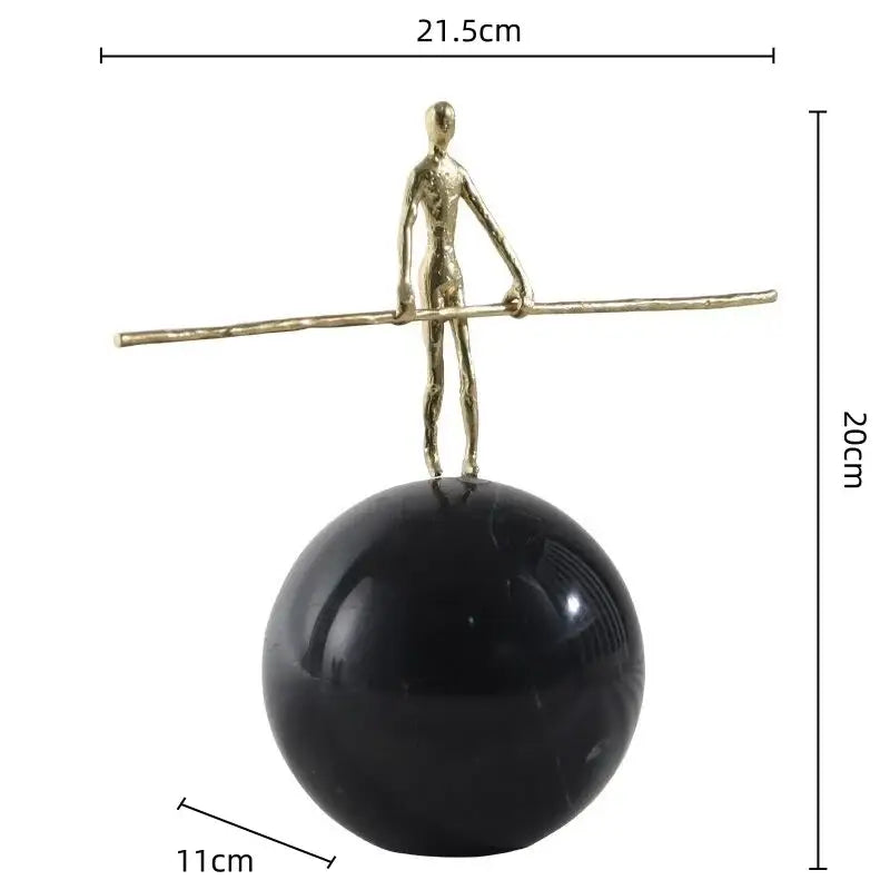 A slender gold-toned golden metal abstract figure sculpture balancing on a polished black marble sphere for living room decor