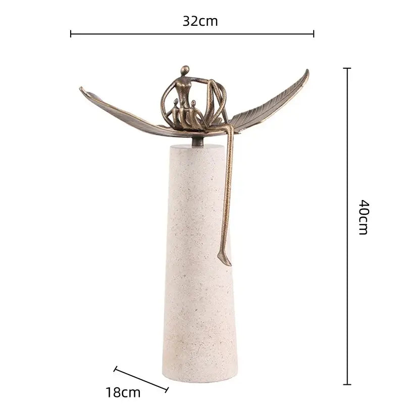 Bronze-colored decorbites golden metal abstract figure sculpture with wings seated on off-white textured base for living room decor