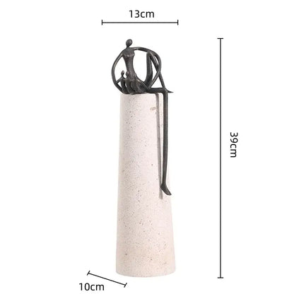 A sleek black metal abstract figure sculpture with intertwined limbs on a textured off-white concrete pedestal decorbites golden metal decor