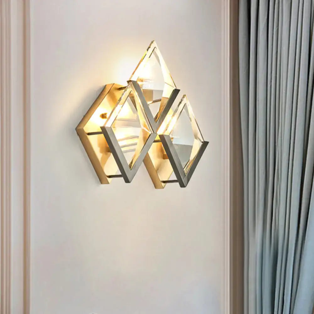 Modern style wall sconce light with clear crystal triangular facets and a dual-tone golden metallic frame for bedroom use