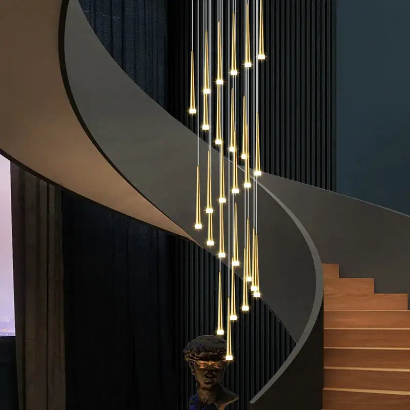 Modern golden tapered chandelier led with slender vertical rods and warm glowing lights above a spiral staircase decorbites golden tapered