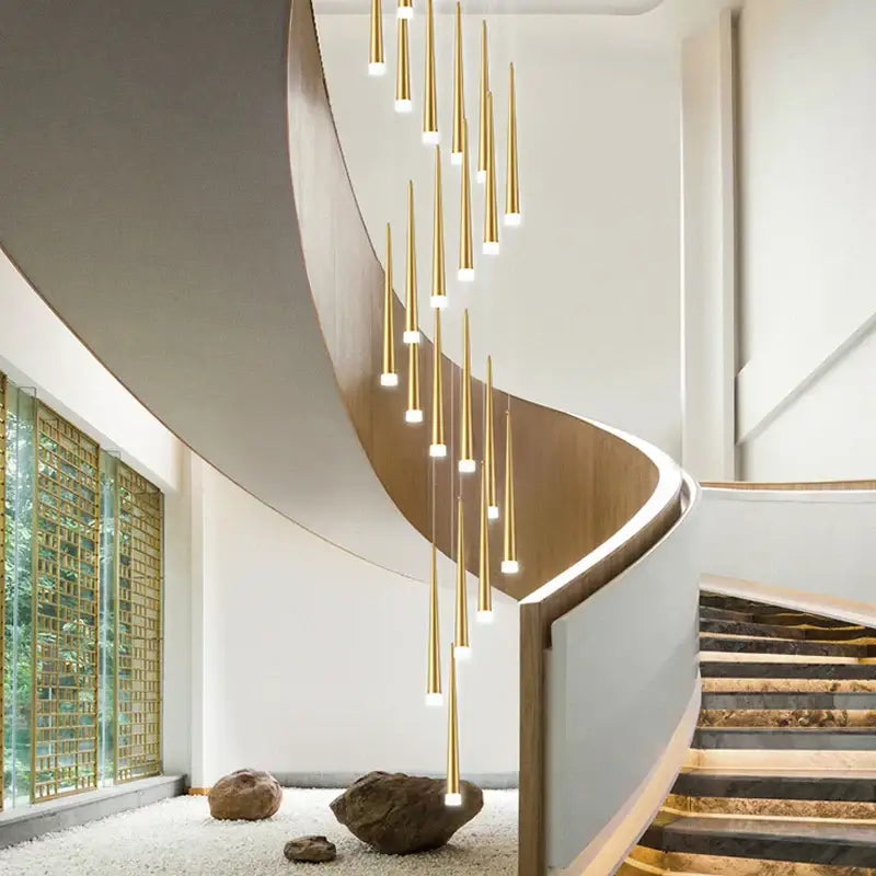 A modern gold-toned decorbites golden tapered led chandelier with slender rods hanging above a curved staircase
