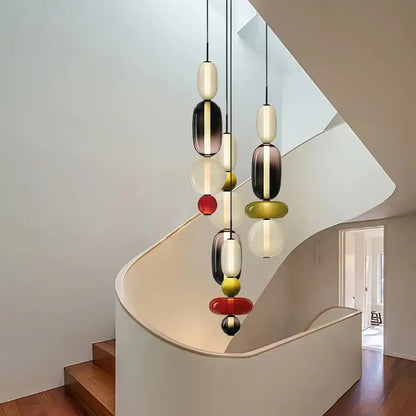 Modern gradient glass pendant light with stacked oval orbs in black white and vibrant red yellow gold for dining room