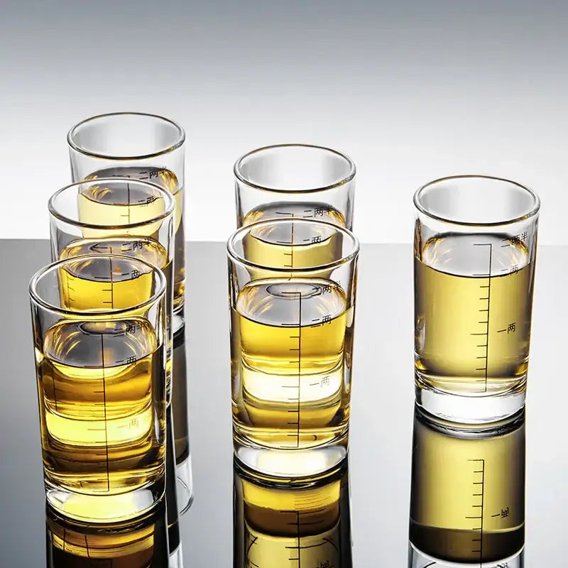 Modern graduated glass spirit set brandy cups with black measurements and chinese characters filled with golden liquid