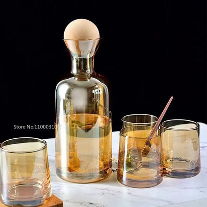 Modern gray amber glass water pitcher with wood stopper and matching amber glass on marble surface for decorbites gray amber