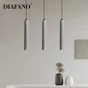 Modern gray concrete tube pendant light with three sleek cylindrical shades hanging from black cords for dining room decorbites concrete tube pendant