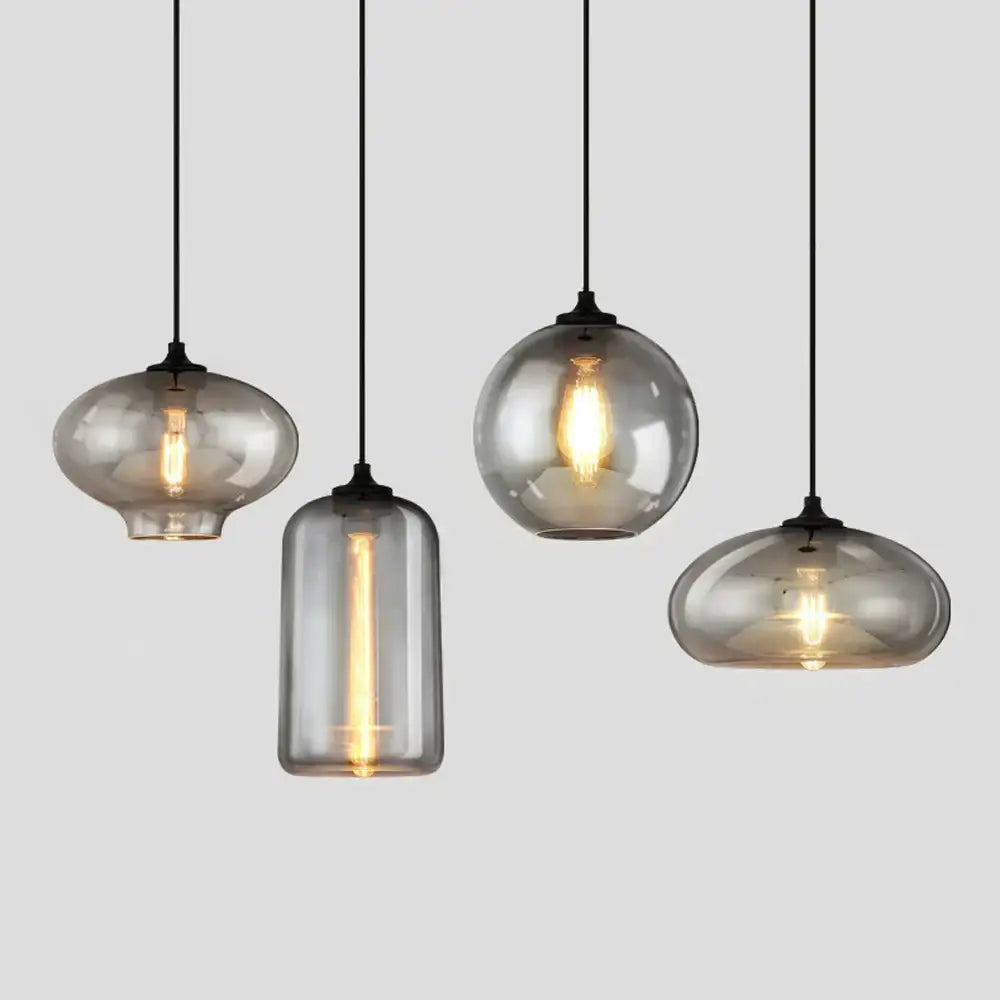 Set of four modern gray glass pendant lights with smoked glass shades and exposed filament bulbs for dining room lighting