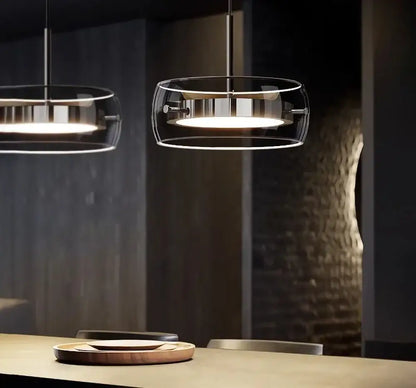 Modern gray glass pendant light with plated detailing and clear glass enclosures emitting warm glow for kitchen
