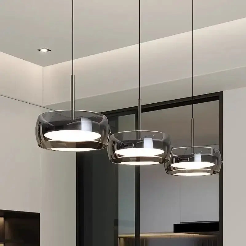 Three modern pendant lights with sleek gray glass and plated detailing designed for kitchen use