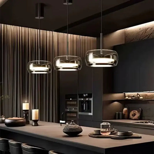 Three modern pendant lights with gray glass shades and plated detailing hang above a kitchen island