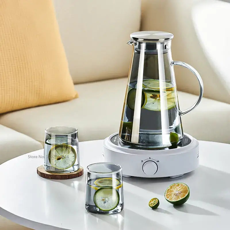 Modern gray glass water pitcher with stainless steel lid and handle filled with water and sliced cucumbers and limes