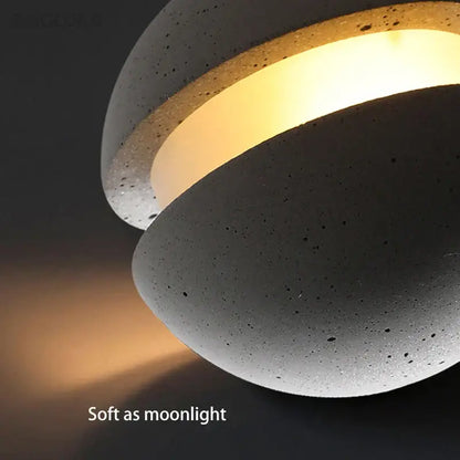 Modern gray and gold cement chandelier with warm glowing inner ring and speckled exterior by decorbites cement chandelier