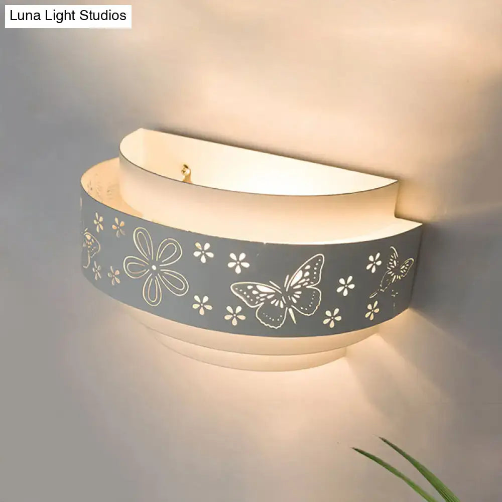 Modern gray metal wall sconce with white butterfly and flower cutouts providing warm living room glow light