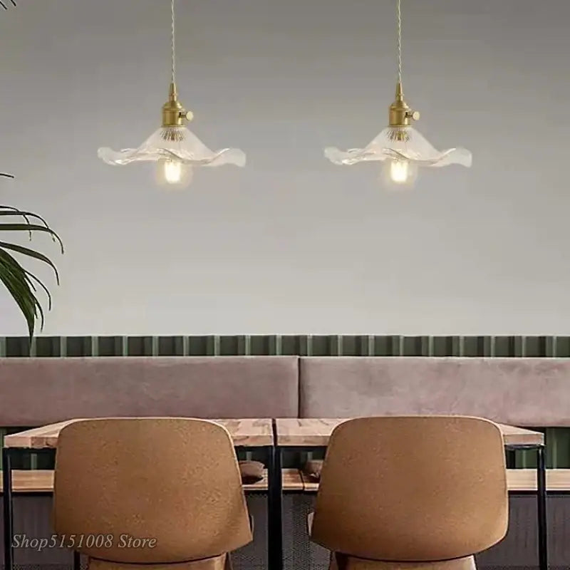 Two elegant brass-finished pendant lights with colorful glass shades hang above a dining area cord pendant installation