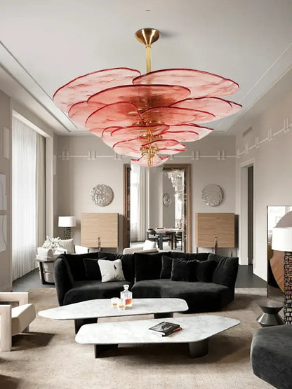 A striking pink layered glass chandelier with a gold-toned fixture complements modern green leaf glass ceiling decor
