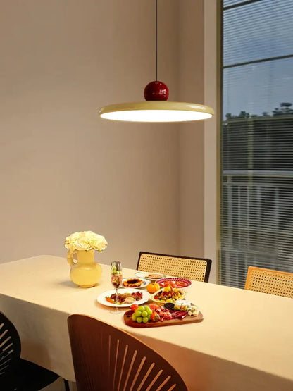 Modern pendant light with a glossy red spherical top and wide cream shade featuring led bulbs for dining room use