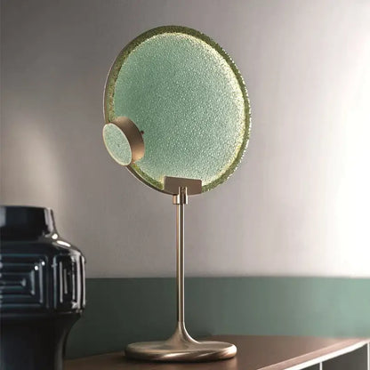 A sleek circular vanity mirror with textured mint green glass and brushed brass frame matching decorbites brass pendant light