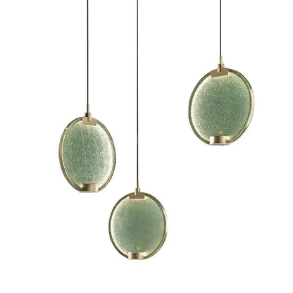 Three oval-shaped pendant lights with textured sage green glass and brass accents decorbites brass pendant light