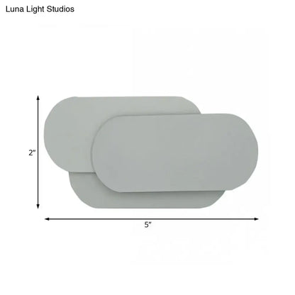 Modern grey oval metal sconce with overlapping panels for bedroom led wall light illumination