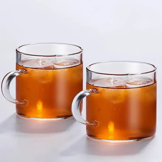 Modern heat resistant clear glass tea cup set with silver handles filled with amber iced tea for dining room use
