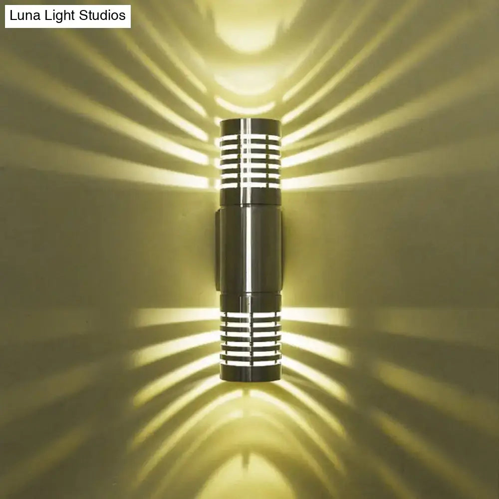Modern black metal wall mounted led sconce with hollow design and horizontal slats casting warm radiant light patterns