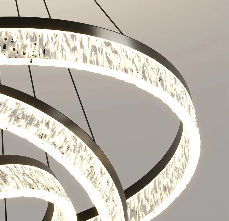 Modern black-framed circular chandelier with textured illuminated glass rings for living and dining room lighting