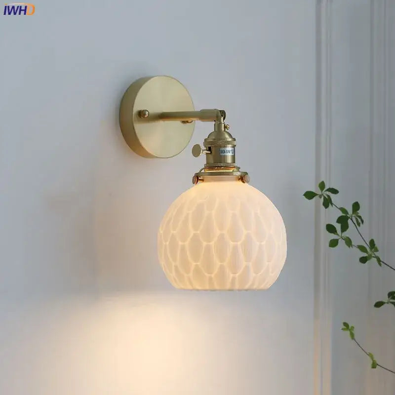 A warm-toned brass modern honeycomb ceramic led wall sconce with frosted glass globe decorbites ceramic led bedroom light
