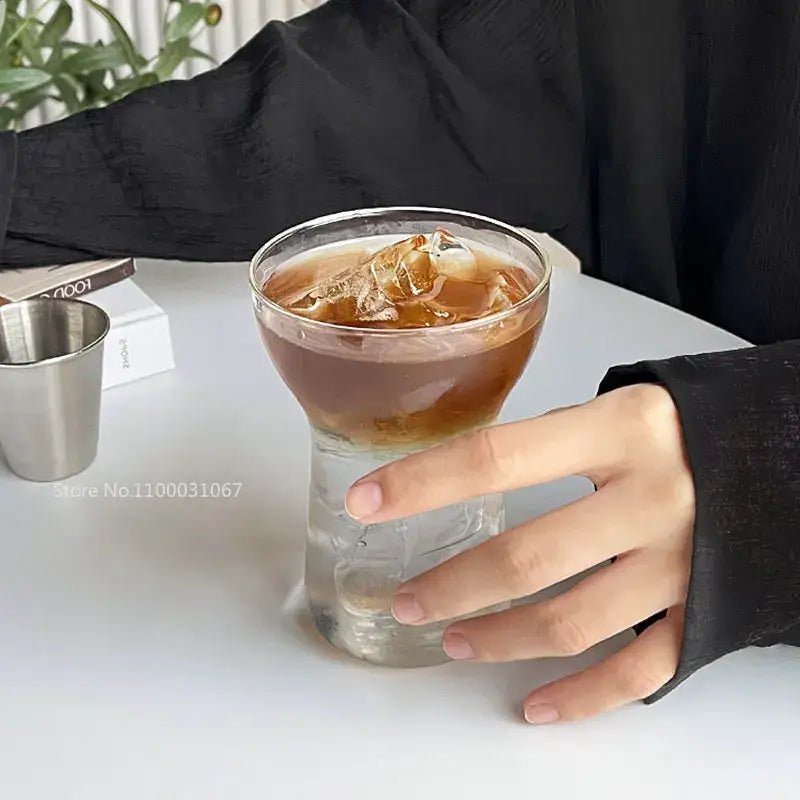 A clear glass drink cup with a textured base and wide rim filled with iced coffee from decorbites drink cup set