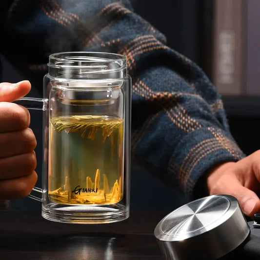 Modern insulated clear glass tea cup with handle lid and transparent chamber holding yellow tea leaves
