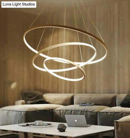 Modern pendant lights featuring three interlocking matte gold rings with warm white led glow for dining room
