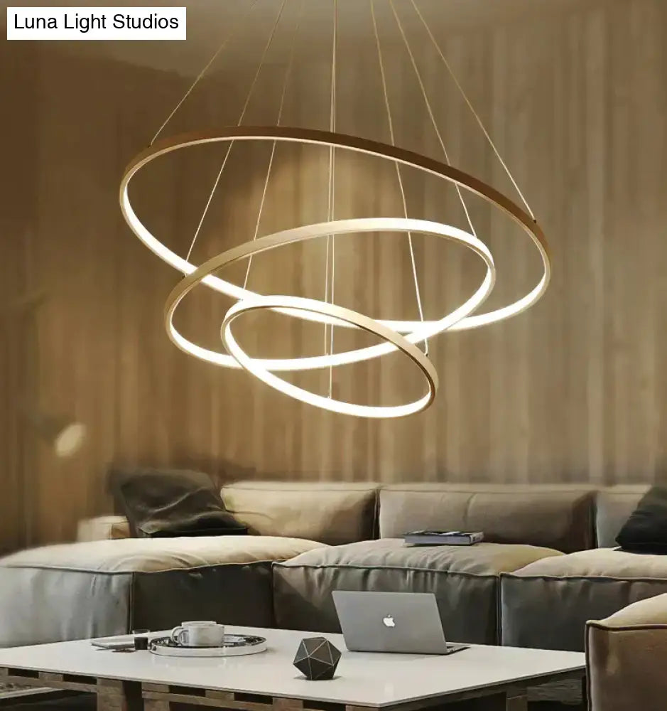 Modern pendant lights featuring three interlocking matte gold rings with warm white led glow for dining room