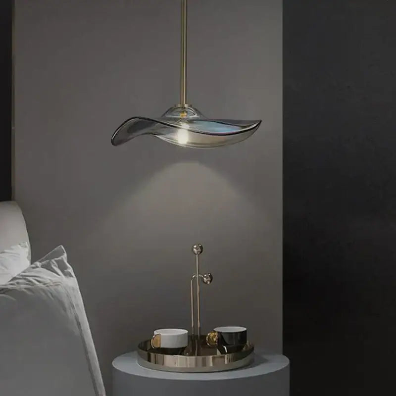 A sleek translucent glass plated pendant lamp with wave design and brass rod for modern kitchen lighting