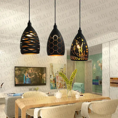 Three black metal pendant lights with intricate cut out patterns hang above a dining table decorbites iron cage pendant light