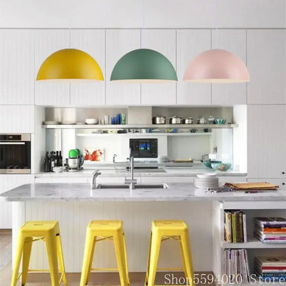 Three colorful matte metal pendant lights in yellow green and pink hang above a kitchen island decorbites iron lustre design
