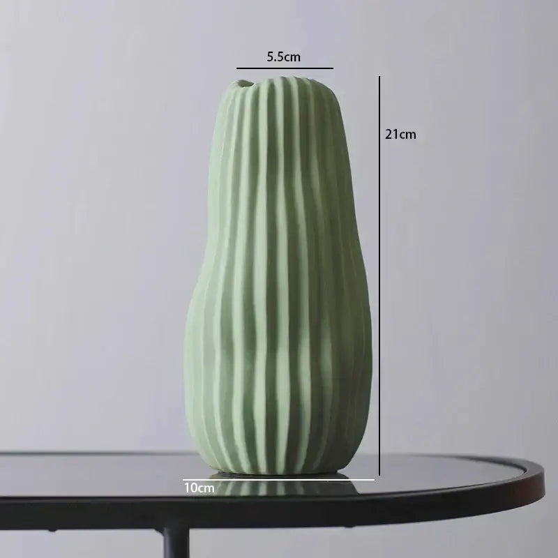 A tall slender mint-green decorbites irregular ceramic vase with vertical ridges for modern living room decor