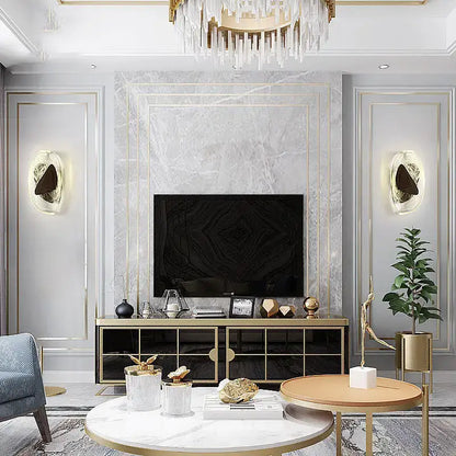 Gold-framed black television mounted on marble wall near modern irregular graphic wall light decorbites irregular graphic sconce