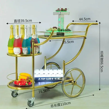 Gold-finished metal beauty salon trolley with glass shelves and wheels featuring a tiered design for salon storage