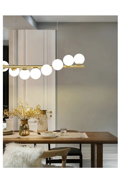 Gold-toned modern LED chandelier with horizontal bar and white glass spherical bulbs for dining room and kitchen lighting