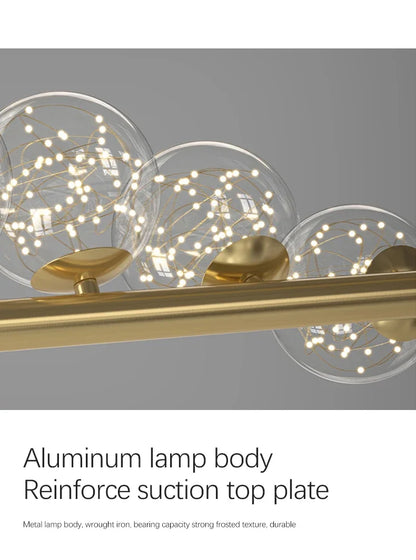 Modern led long ceiling chandelier with brass finish and three clear glass spheres containing delicate string lights
