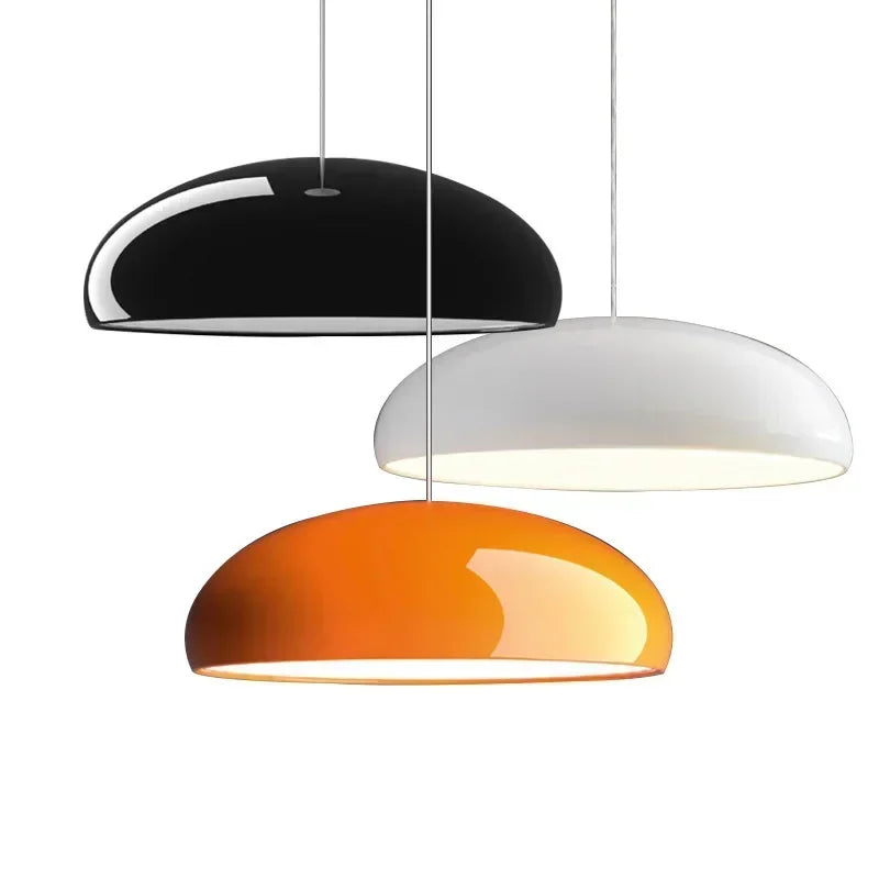Three sleek dome-shaped pendant lights in black white and orange with round aluminum lampshades for modern decor