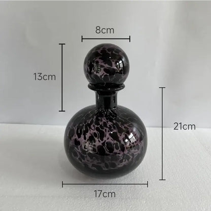 A glossy black glass perfume bottle with marbled purple stopper in modern leopard texture glass decorbites style