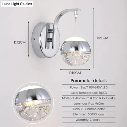 Modern luxurious crystal led wall sconce with chrome finish, curved arm, and illuminated k9 crystal bubble glass globe