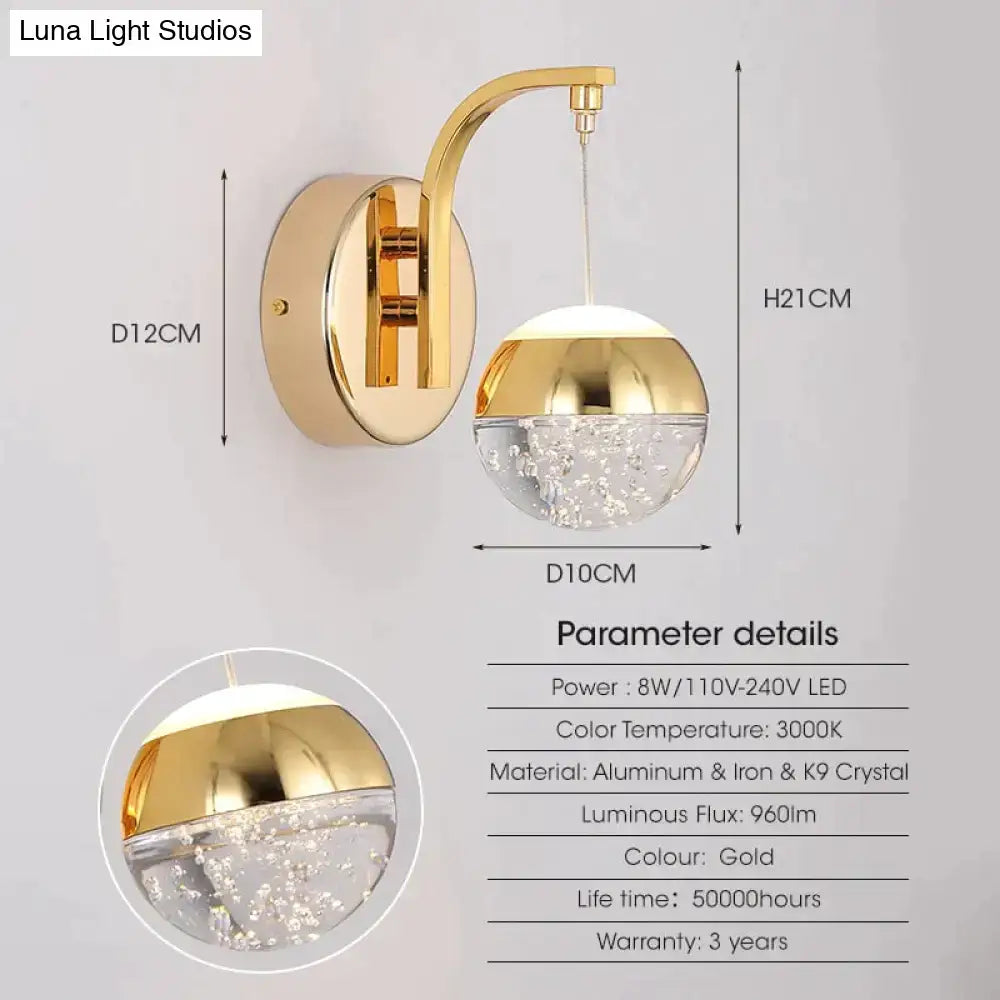 Modern luxurious crystal led wall sconce with gold finish curved arm and spherical globe for bedroom lighting