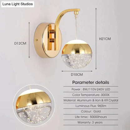 Modern luxurious crystal led wall sconce with gold finish curved arm and spherical globe for bedroom lighting
