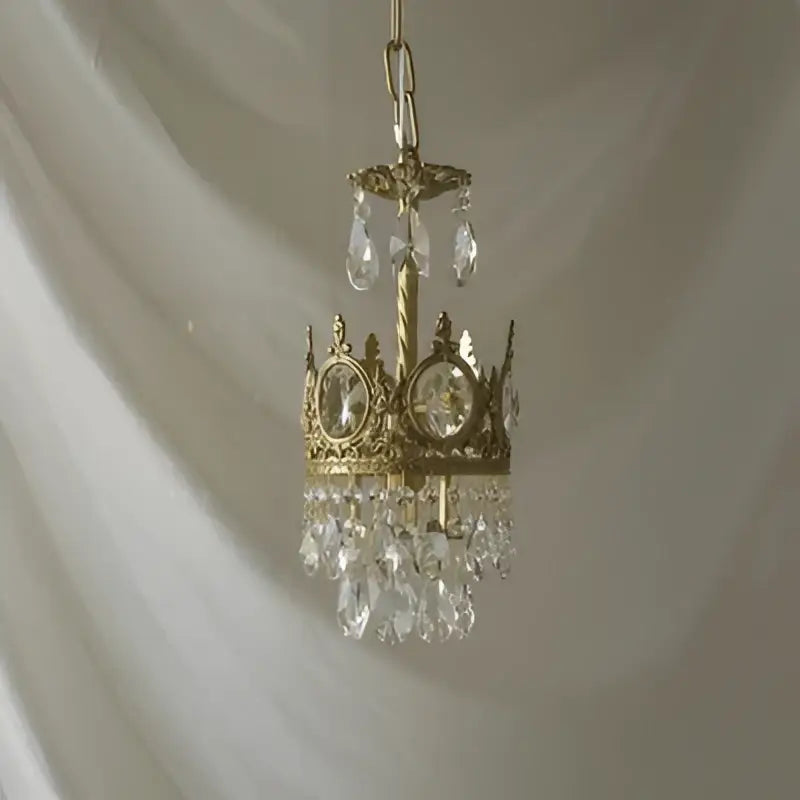 A delicate gold-toned decorbites crystal crown chandelier with clear crystals and oval stones for living room decor