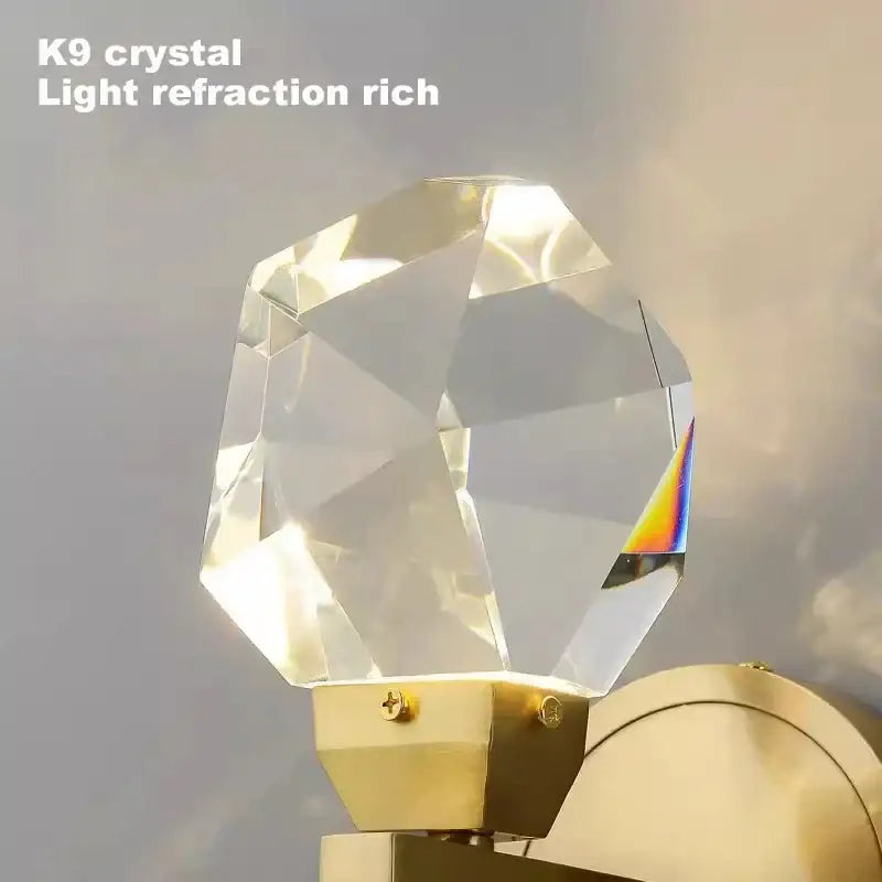 Modern luxury gold crystal led wall sconce featuring a faceted k9 crystal with rich light refraction on a gold base
