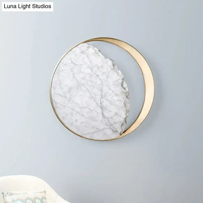 A circular wall light featuring a white marble gold led slab with gray veining in a sleek gold led wall frame