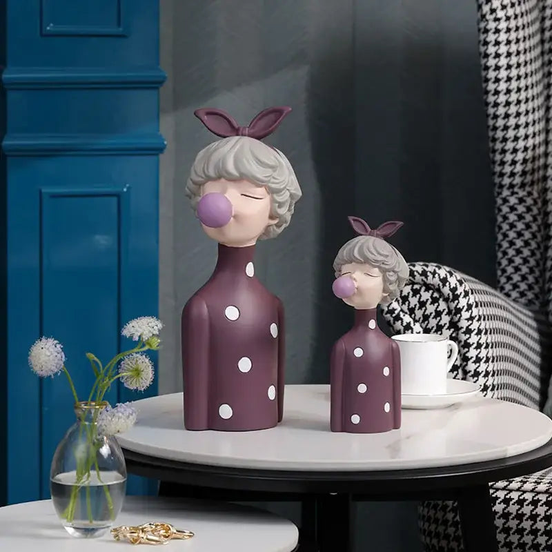 Two purple polka-dotted bubble gum girl statues with gray hair and bunny ears for modern maroon and silver bedroom decor