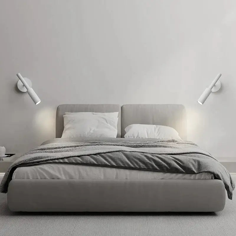 Modern matte black adjustable led wall lamp installed above a gray upholstered bed with matching headboard and footboard